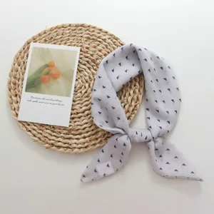Detailed view of a light grey small square scarf with blue triangle pattern, neckerchief.