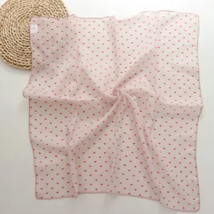 Close-up detail of the pink square scarf featuring delicate red geometric triangle patterns.