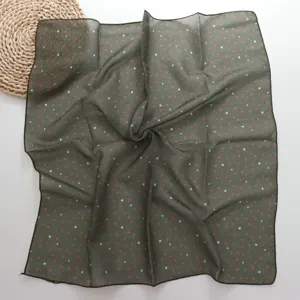 Detailed view of the dark green polka dot small square scarf showing fabric and pattern.