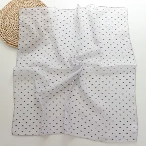 Detail shot of white cotton linen small square scarf with blue geometric triangle pattern.