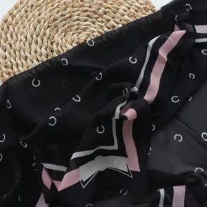 Chic black chiffon square scarf with white monogram print and stylish pink striped border.