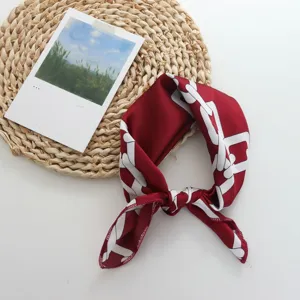 Detailed view of a burgundy silk small square scarf with a white geometric chain print.