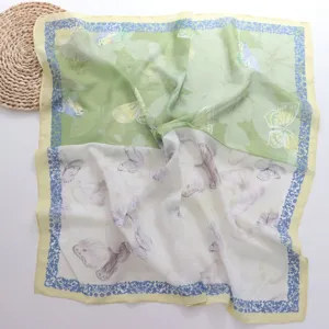 Detailopname van de groen-witte zijden sjaal met een delicaat vlinder- en bloemenprintpatroon.
