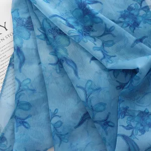 Gros plan detail de la texture du foulard leger bleu avec un motif floral elegant.