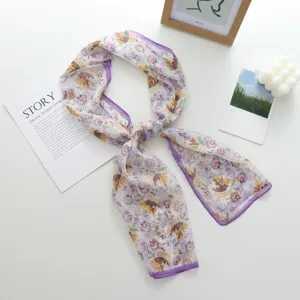 Gros plan détaillé de l'écharpe longue et fine à motif floral avec bordure violette.