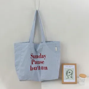 Detailansicht der blau-weiß gestreiften Canvas-Tasche mit rotem Buchstaben-Druck.