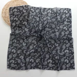 Primer plano de los detalles de la textura del pañuelo cuadrado con estampado paisley en blanco y negro.