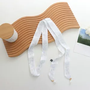 Vue détaillée du foulard ruban blanc à fleurs avec pendentifs en perles élégants.