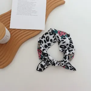 Gros plan d'un foulard carré en soie à imprimé léopard noir et blanc avec des fleurs.
