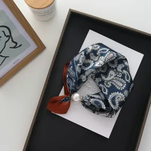 Gedetailleerd overzicht van een stijlvolle paisley zijden sjaal met grote parel magnetische gesp.
