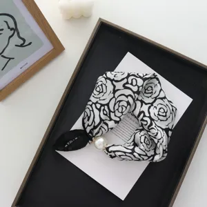 Primo piano dettagliato di foulard in seta con stampa di rose e fibbia magnetica di perle.