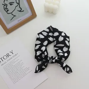 Détail de foulard en soie à imprimé abstrait noir et blanc, parfait pour coiffure ou accessoire.