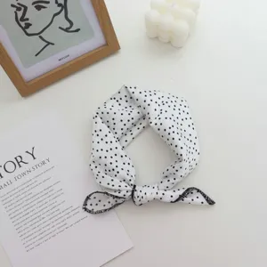 Vue détaillée du bandeau foulard en soie à pois noir et blanc dans un décor minimaliste.