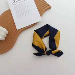 Détail d'un petit carré de soie à rayures géométriques bleu et jaune, accessoire polyvalent.