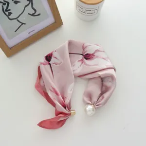 Roze zijden sjaal met bloemenprint, parel en magneetsluiting als elegant mode-accessoire.