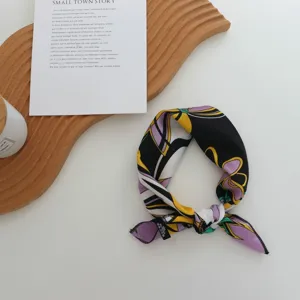 Vue détaillée du foulard géométrique en soie artificielle avec nœud et belle texture.
