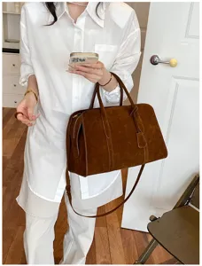 Close-up of retro brown suede Boston handbag with shoulder strap in daily lifestyle scene.