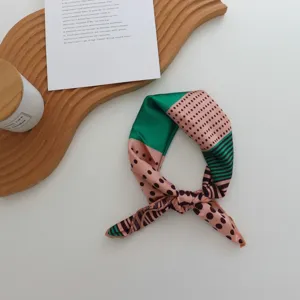 Vue détaillée d'un petit carré de soie imitation à motif de rayures géométriques et de pois.