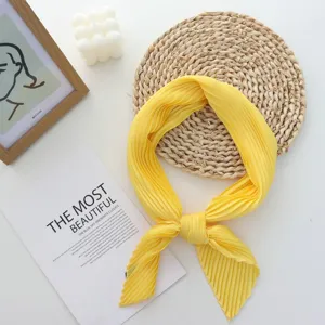 Detailed view of the elegant yellow pleated square scarf, highlighting its soft fabric and fine folds.