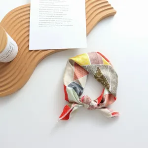 Gros plan sur le carré de soie géométrique imprimé, accessoire de cou et de cheveux élégant.