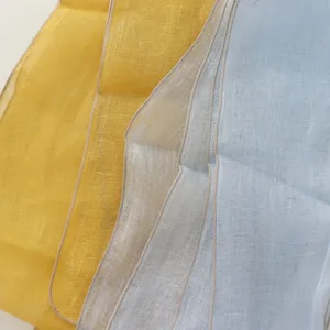 Close-up detail of long linen scarf fabric in vibrant yellow, beige and light blue colors.