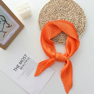 Detailed view of orange pleated square silk scarf, soft fabric texture and elegant knot style.