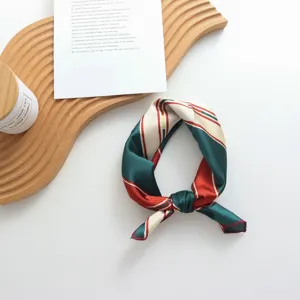 Gros plan d'un foulard en soie géométrique chic avec des rayures vertes et rouges, parfait.