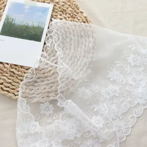 Close-up of exquisite white floral lace fabric, featuring delicate floral embroidery.