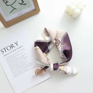 Gros plan d'un foulard en soie élégant à motif de chaîne géométrique sur un bureau blanc.