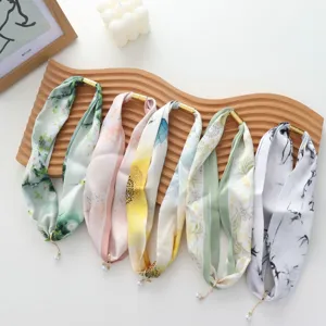 Detailed shot of stylish long silk scarves with magnetic buckle and pearl pendant charms.
