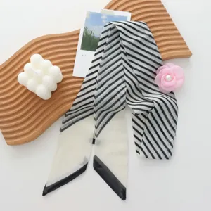 Close-up view of a chic black and white striped skinny scarf with a pink rose accessory.