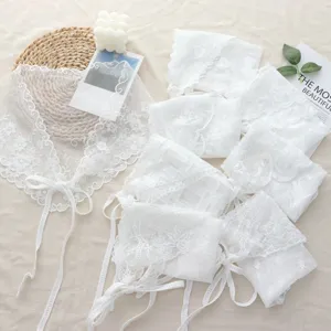 Detailed close-up view of white lace ruffle triangle headscarf and layered fashion accessories.