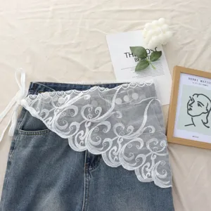 Detail shot of blue denim layered skirt with elegant white floral lace trim, aesthetic flat lay style.