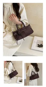 Vue détaillée du sac à main marron en daim chic avec boucle métallique et pendentif.