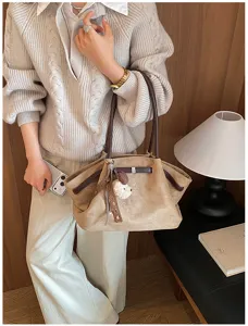 Gedetailleerd overzicht van de retro suède tote tas gedragen door het model, met textuur.