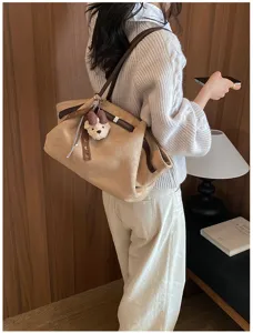 Gedetailleerd uitzicht van retro suède tote tas met schattige berenhanger en stijl.