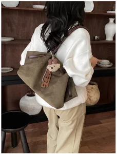 Gedetailleerd overzicht van de retro suède tote tas met zachte textuur en schattige berenhanger.