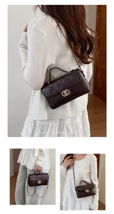 Detail view of a chic quilted crossbody bag with metal chain strap and elegant handle.
