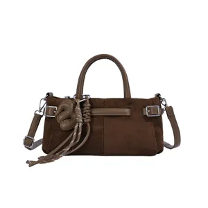 Sac bandoulière rétro en suédine marron avec pendentif nœud stylé et poignée.