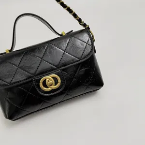 Close-up detail shot of a black quilted crossbody bag featuring a chic gold chain and clasp.