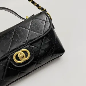 Black quilted leather mini shoulder bag with gold chain strap and elegant handle detail.