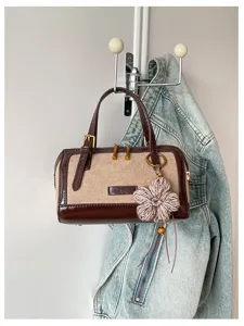 Detail shot of a retro color-blocked Boston handbag with knit flower charm and metallic hardware.