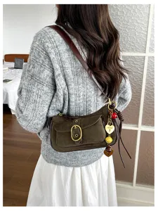 Retro style suede shoulder bag detail featuring metallic buckle and hanging charms.