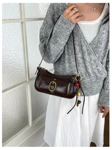 Close-up detail of dark brown vintage underarm shoulder bag with metallic buckle and charms.