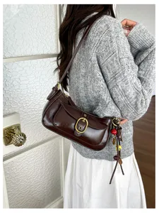Retro brown leather shoulder bag detail shot showing metal buckle and cute hanging charms.