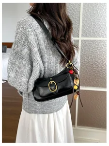 Classic black leather shoulder bag with metal buckle and cute charms for women daily wear.
