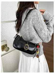 Black leather underarm shoulder bag with metal buckle detail and charm for women daily wear.