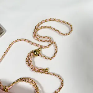 Pink leather woven gold chain strap with adjustable metal ball accessory for luxury fashion bags.