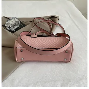 Dettaglio borsa a tracolla rosa in patchwork intrecciato, con texture e borchie in metallo.
