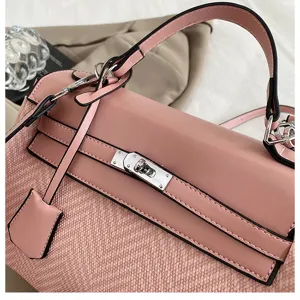 Dettaglio di una borsa da donna rosa in pelle e tweed con chiusura metallica.